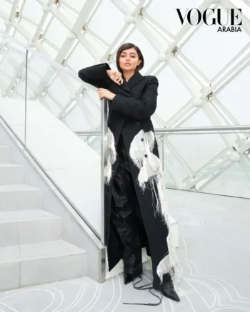 Saudi Fashion and beauty influencer, Eleen Su wearing a black coat and black leather pants near the stairs.